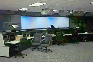 Network operations center with curved desks facing a large projected video wall