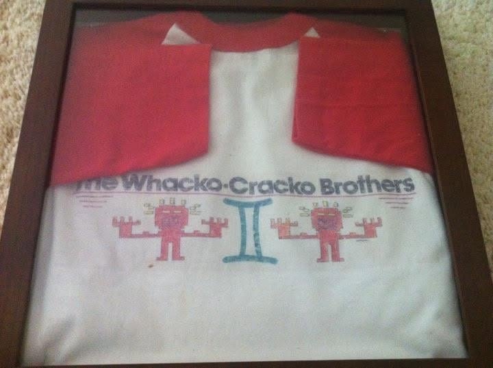 Framed white baseball-style t-shirt with red raglan sleeves reading The Whacko-Cracko Brothers, with twin red cartoon figures flanking a light-blue Gemini symbol